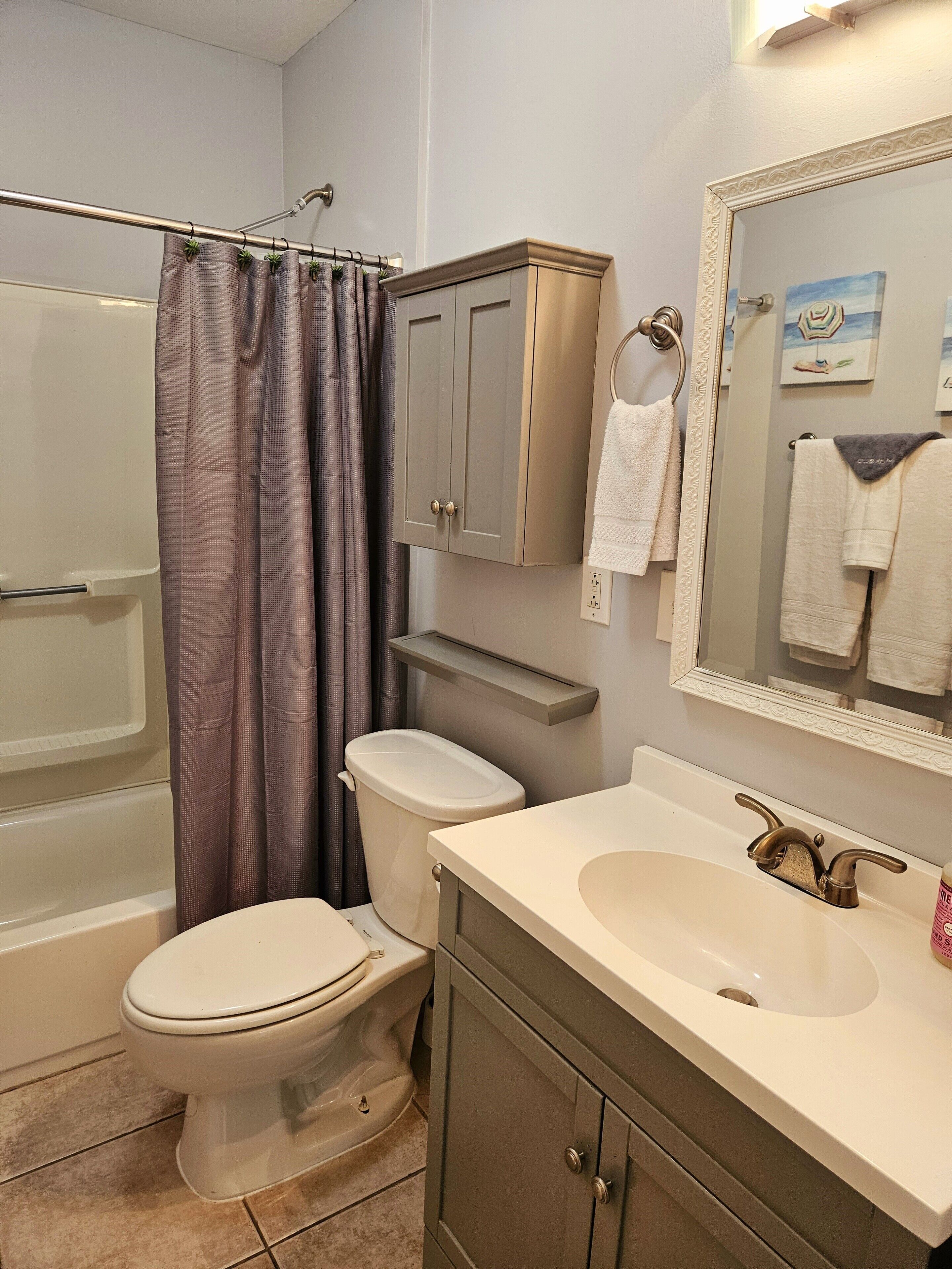 Ein Badezimmer mit Toilette, Waschbecken, Spiegel und Dusche.