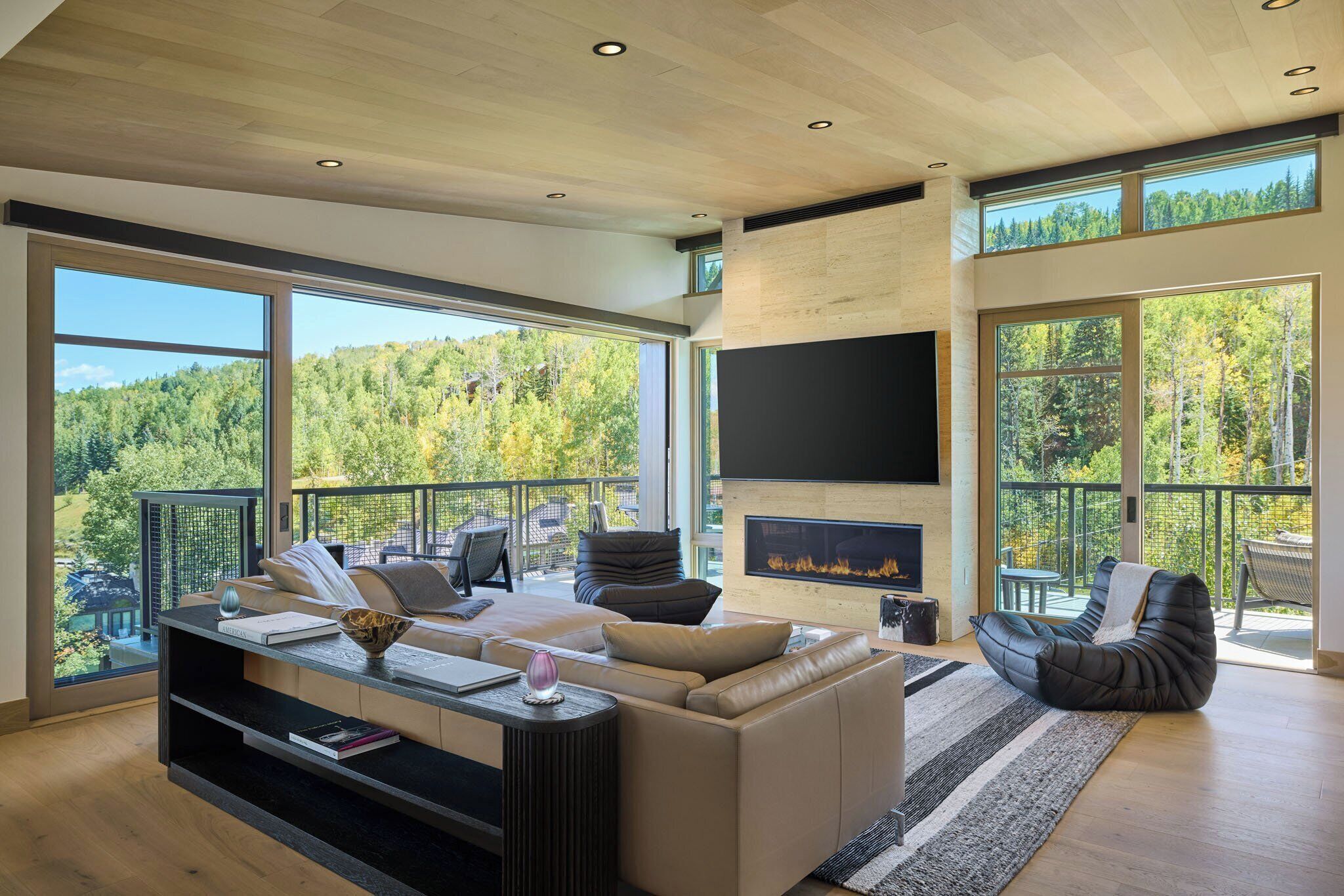 A modern living room with a large sofa, a flat-screen TV, and a fireplace.