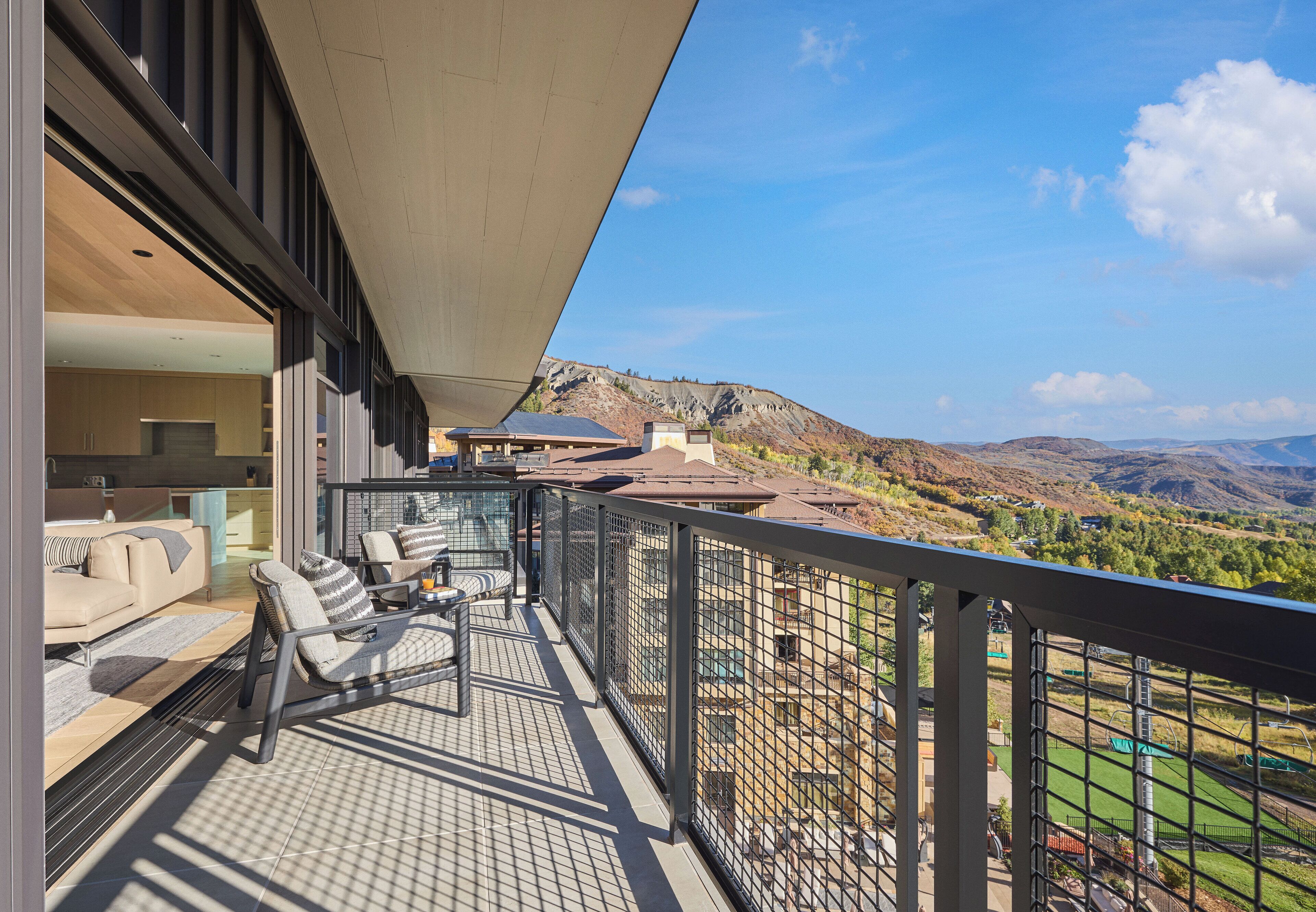 A balcony with a view of mountains and a pool.