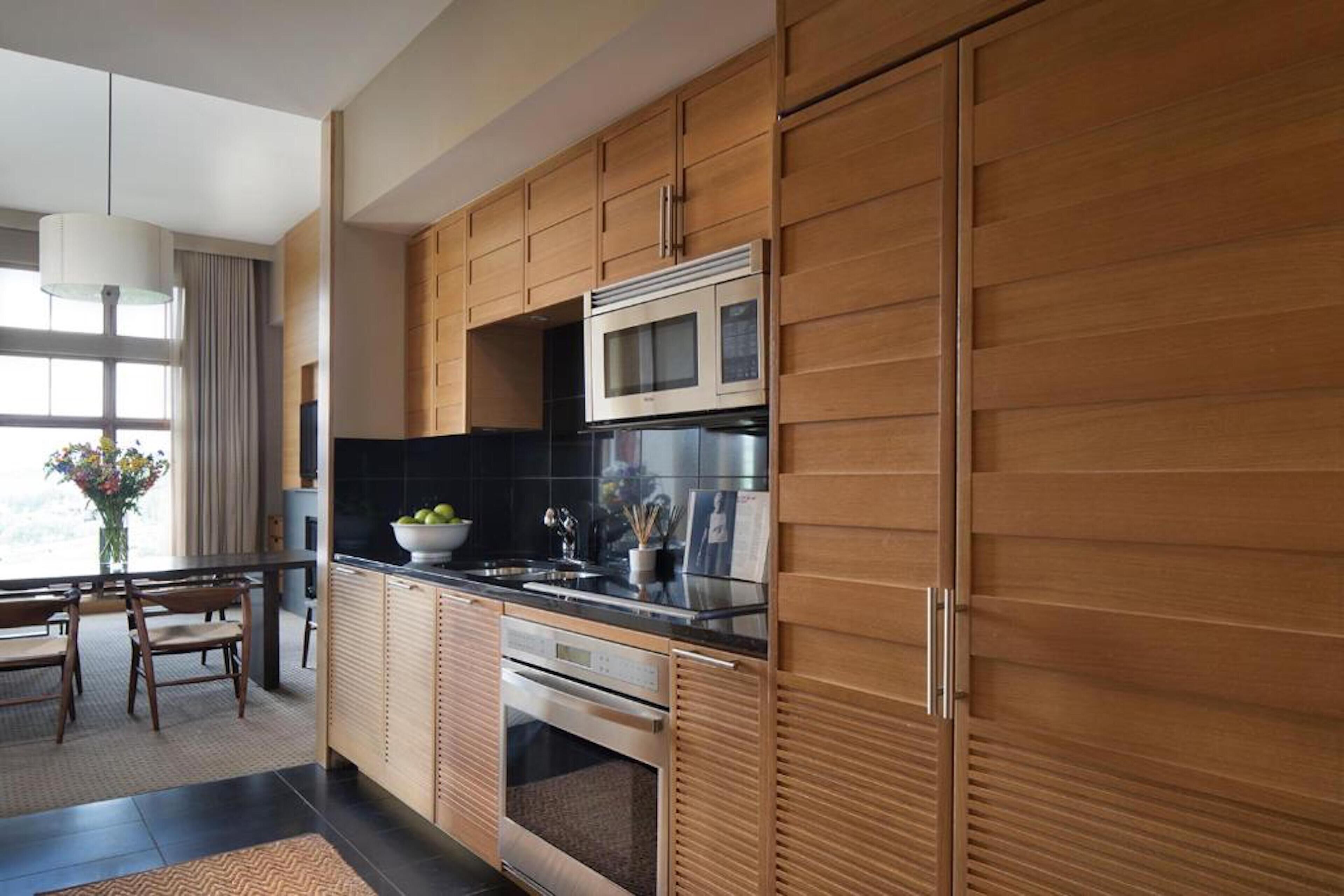 A modern kitchen with wooden cabinets, stainless steel appliances, and a black countertop.
