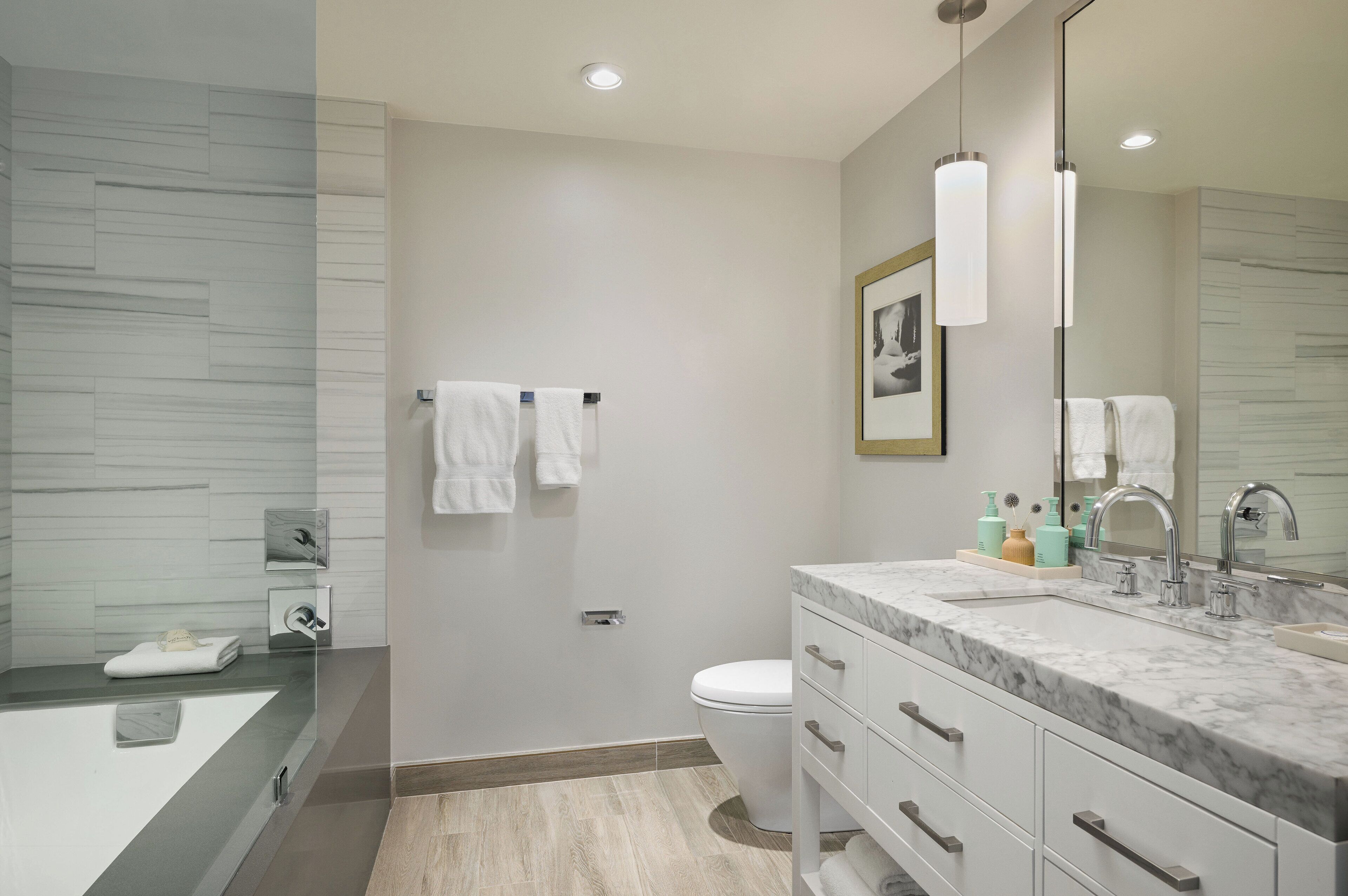 A modern bathroom with a marble sink, a toilet, and a bathtub.