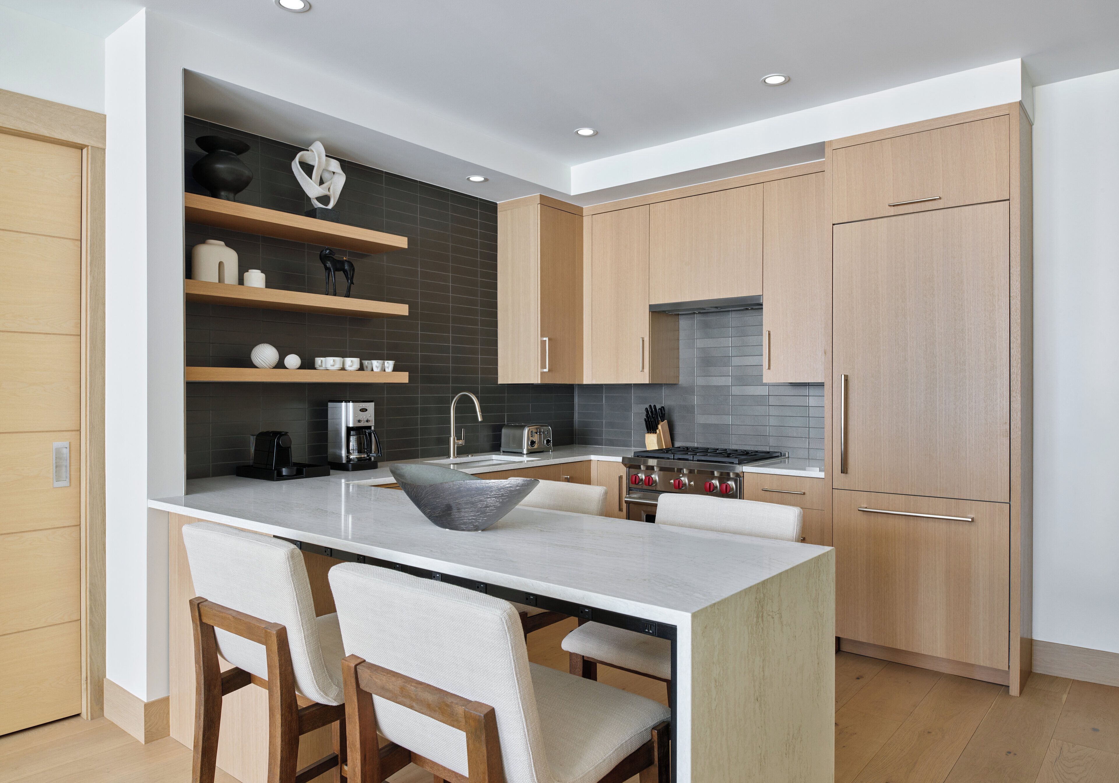 A modern kitchen with a central island, wooden cabinets, and a stainless steel range hood.