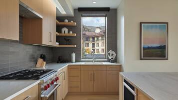 A modern kitchen with wooden cabinets, a stainless steel stove, and a window with a view of buildings.
