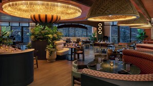 Um restaurante amplo com pé direito alto, grandes janelas e diversos tipos de assentos, incluindo mesas e cabines.
