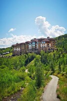 Un hotel de varios pisos con un patio central, rodeado de abundante vegetación y un sendero serpenteante.
