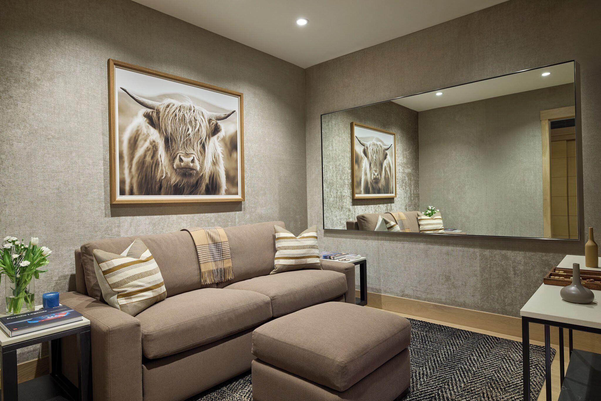 A modern living room with a sofa, a coffee table, and a large mirror.