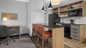A modern kitchen with a wooden countertop, two pendant lights, a refrigerator, microwave, and a coffee maker. - Candlewood Suites Hotel Texas City by IHG (Texas City)