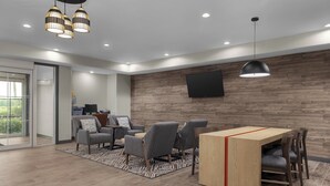 A modern living room with a wooden accent wall, a flat-screen TV, and a dining area with a wooden table and chairs. - Candlewood Suites Hotel Texas City by IHG (Texas City)