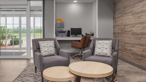 A modern office space with two grey armchairs, a wooden table, and a desk with a computer and printer. - Candlewood Suites Hotel Texas City by IHG (Texas City)