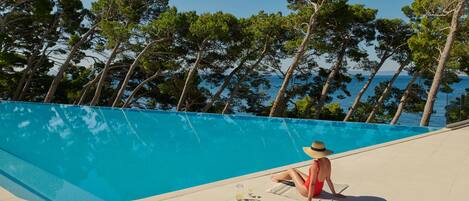 A person sitting by a pool with a view of trees and water.