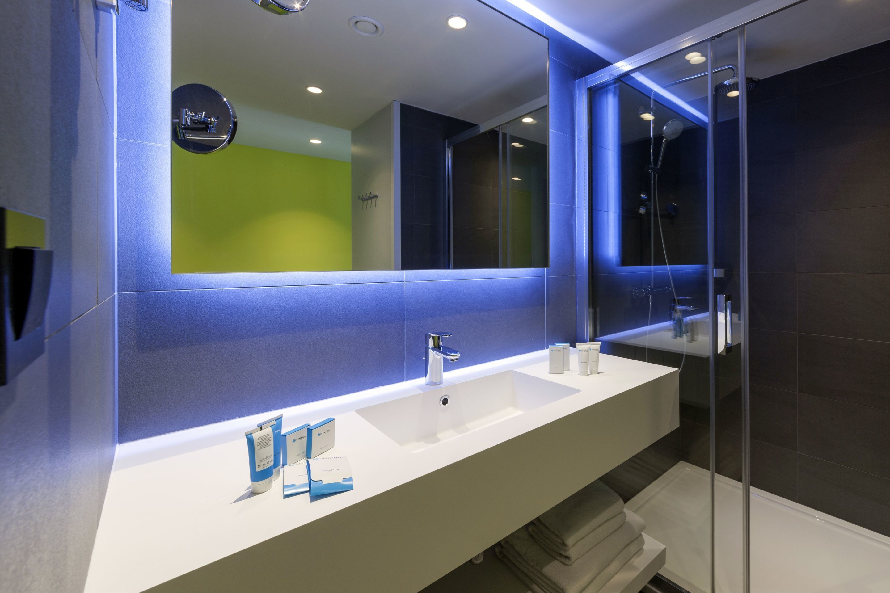 A modern bathroom with a white sink, a large mirror, and a glass shower enclosure.