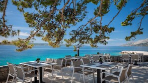 An outdoor seating area with tables and chairs overlooking a body of water.