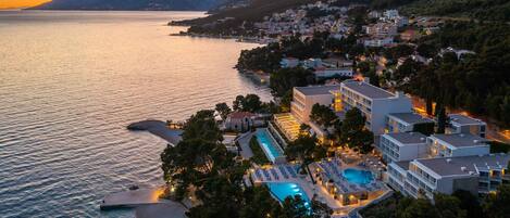 A coastal hotel with a pool, beach access, and mountain views.