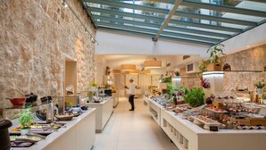 A modern hotel kitchen with a glass ceiling, stone walls, and a variety of food stations.