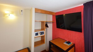 A compact hotel room with a wooden desk, a built-in wardrobe, a coat rack, and a large window. - Centro 19 Hotel (Querétaro)