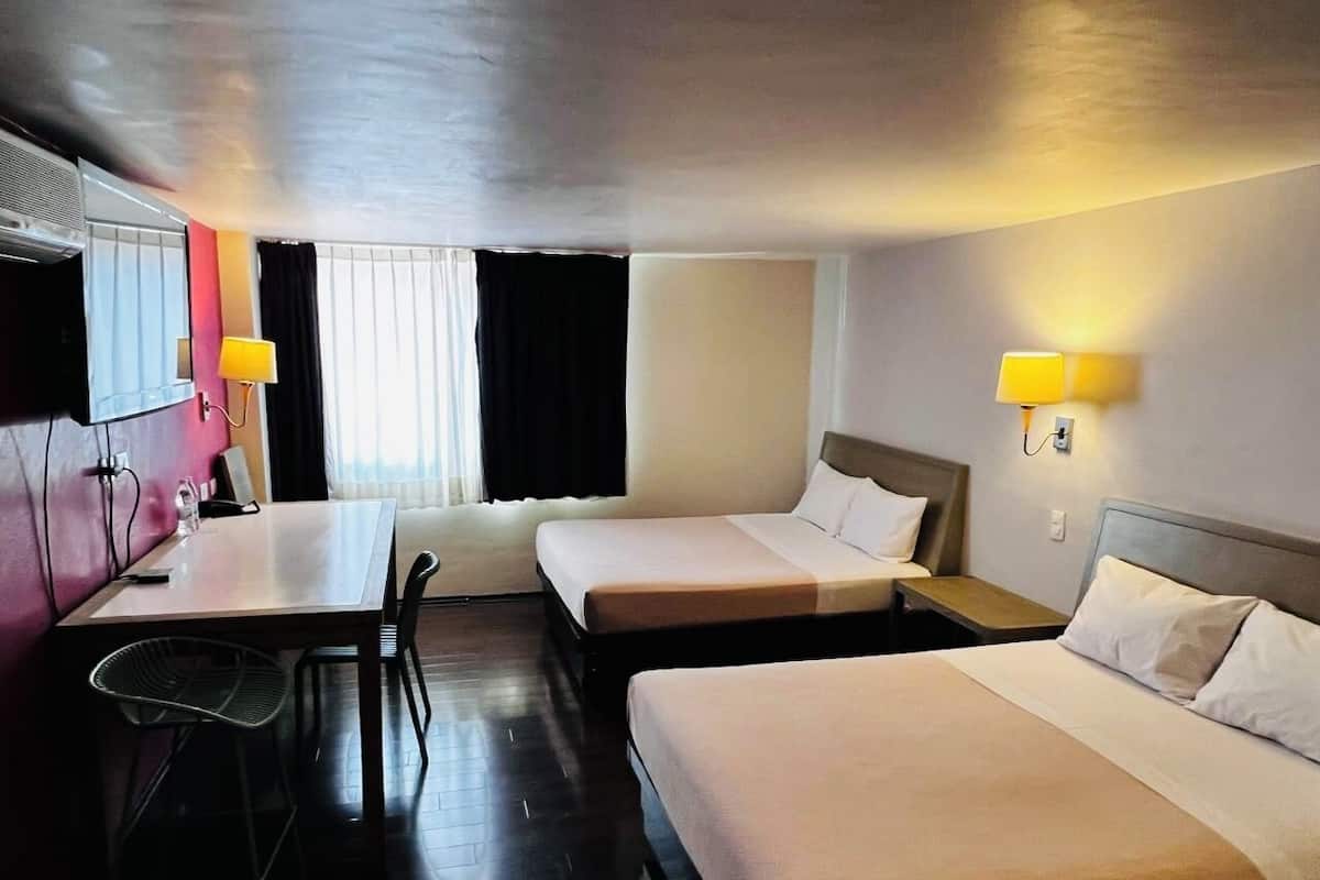A hotel room with two beds, a desk, and a chair.