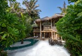 A resort with a pool, lounge chairs, and a thatched-roof structure.