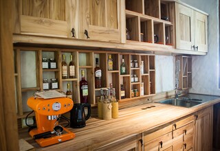 A kitchen with wooden cabinets, a coffee machine, and various bottles and jars.
