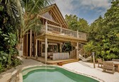 A wooden house with a balcony, a pool, and outdoor furniture.