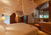 A bedroom with a canopy bed, wooden furniture, and a view of the outdoors.
