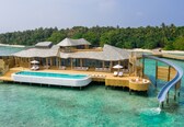 A luxurious overwater villa with a swimming pool, multiple decks, and a slide leading into the water.