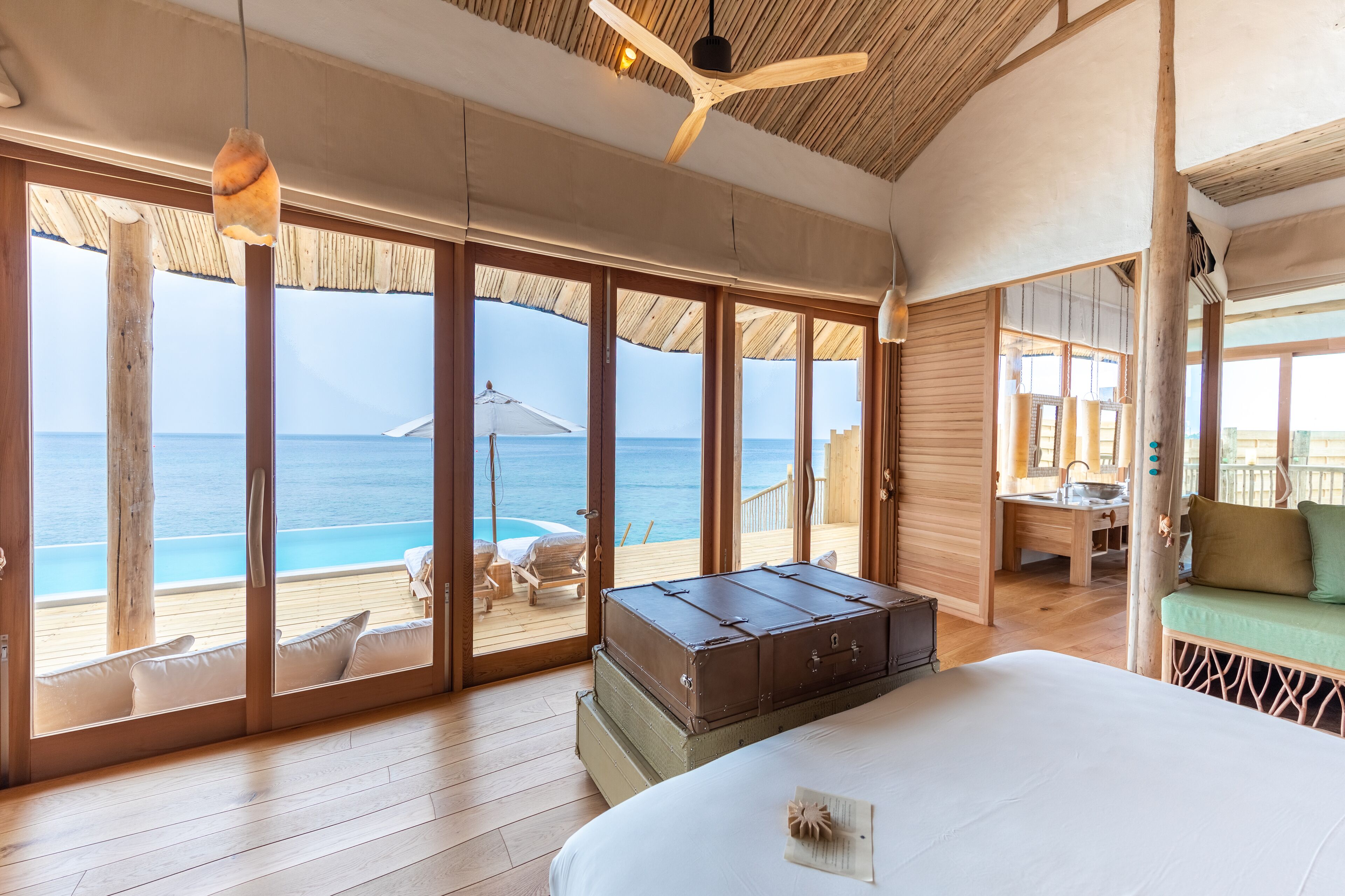 A spacious room with a large bed, wooden floor, and a view of the ocean.
