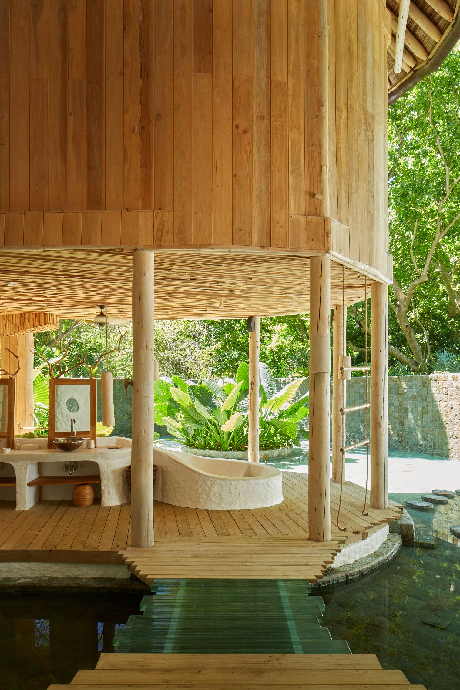 Una estructura de madera con piscina, escalones de piedra y un muro de piedra.