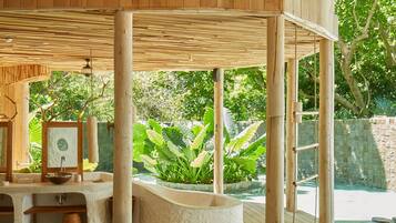 Una estructura de madera con piscina, escalones de piedra y un muro de piedra.