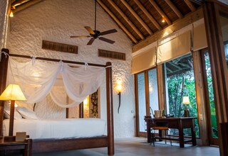 A bedroom with a four-poster bed, a ceiling fan, and a desk with a chair.
