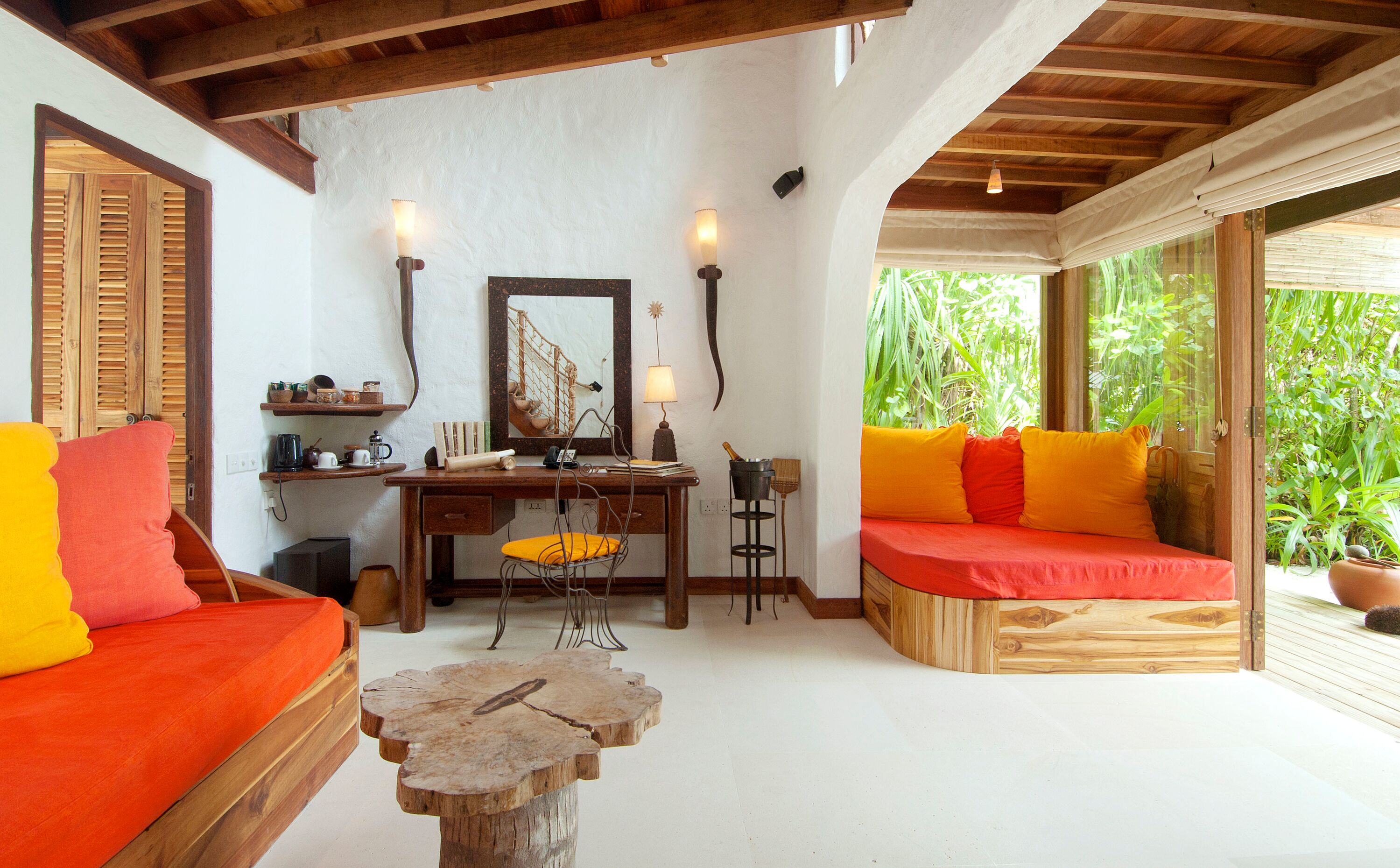 Una habitación acogedora con un escritorio de madera, un banco acolchado y una mesa de centro de madera.