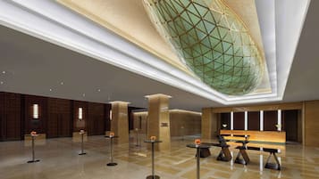 A spacious lobby with a high ceiling, a large decorative glass structure, and modern furniture.