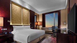 Une chambre d’hôtel avec un grand lit, un bureau, une chaise et une vue sur la ville.