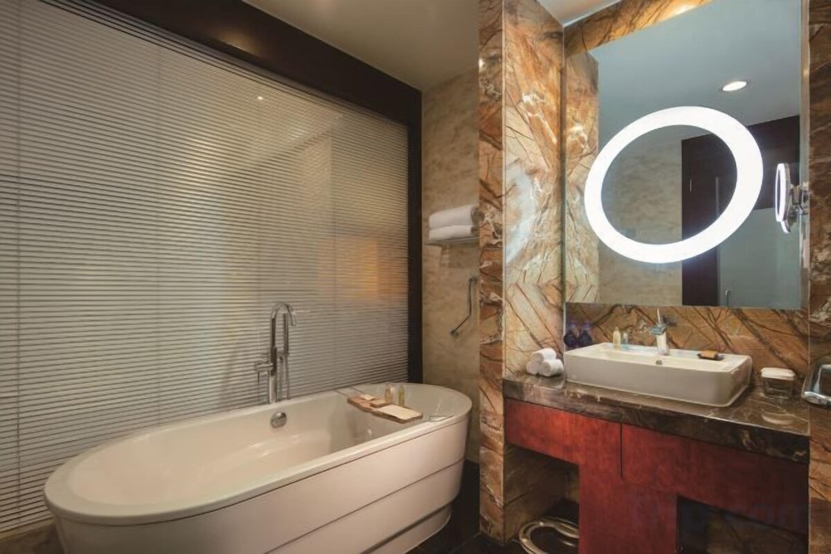 A modern bathroom with a freestanding bathtub, a vanity with a mirror, and a marble backsplash.