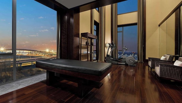 A spacious room with a large window, a massage table, exercise equipment, and a seating area.