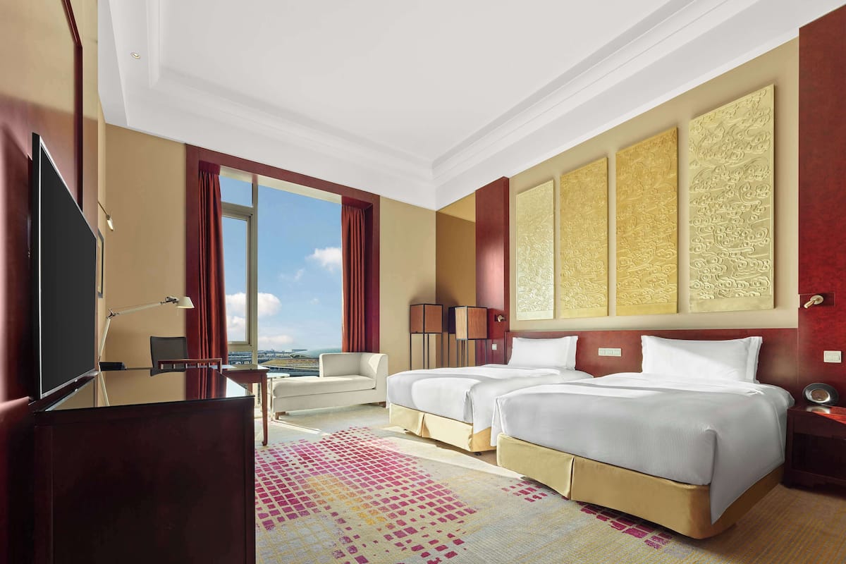 Habitación de hotel con una cama grande, un escritorio, una silla y vistas a la ciudad.