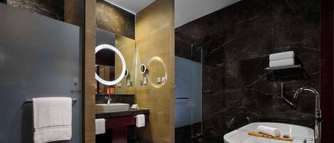 A modern bathroom with a large bathtub, a vanity with a mirror, and a shower area.