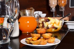Impostazione colazione con una brocca di succo d'arancia, una ciotola di frutta e dolci su un tavolo.