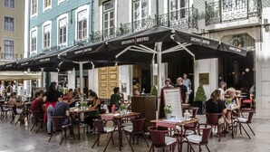 Un café en plein air avec des tables et des chaises, un panneau affichant le menu, et un bâtiment dont l’enseigne indique « BROWN’S BISTRO » au fond.