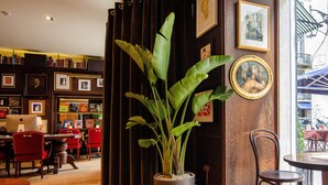 L’intérieur chaleureux du restaurant est agrémenté de meubles en bois, d’une grande plante en pot et d’œuvres d’art encadrées qui ornent les murs.