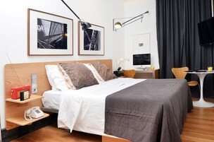 A modern hotel room with a bed, bedside tables, a desk, and a TV.