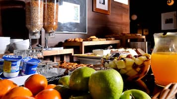 A breakfast buffet with various food items, including fruits, pastries, and beverages.