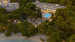 An aerial view of a hotel with a swimming pool, surrounded by dense trees and a beach. - Maestral Adults Exclusive Hotel (Brela)