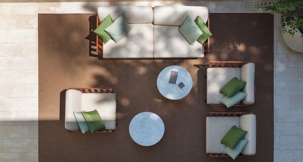 Un espacio al aire libre con sofás, dos sillones y una mesa redonda.