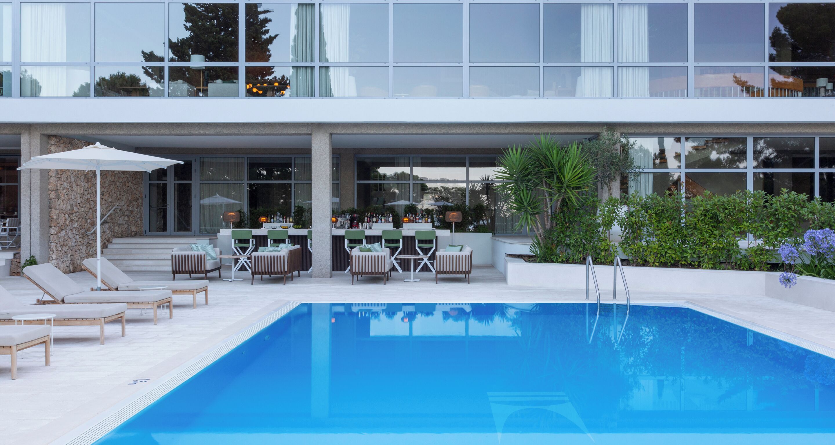 Un hotel moderno con piscina, zona de estar al aire libre y bar.