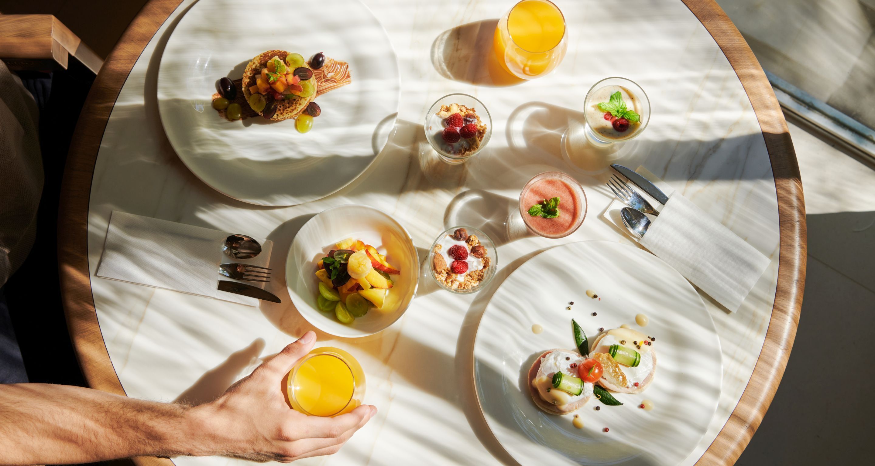Une table ronde dressée pour le petit-déjeuner, avec différents plats et boissons.