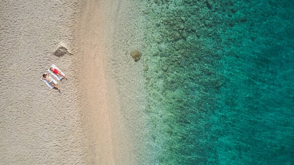 An aerial view of a beach with clear turquoise water and a sandy shore. - Maestral Adults Exclusive Hotel (Brela)