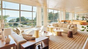 A spacious living area with large windows, a sofa set, and a coffee table. - Maestral Adults Exclusive Hotel (Brela)