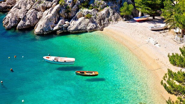 A beach with clear turquoise water, rocky cliffs, and boats. - Maestral Adults Exclusive Hotel (Brela)