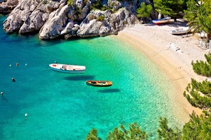 Una playa con aguas turquesas cristalinas, acantilados rocosos y barcos.
