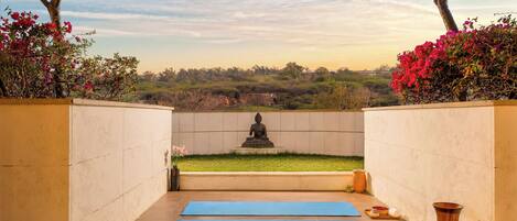 A meditation area with a statue, blue mats, and a view of a landscape.